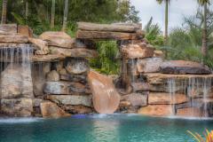 Waterslide exit splashing into sparkling pool with tropical design elements.